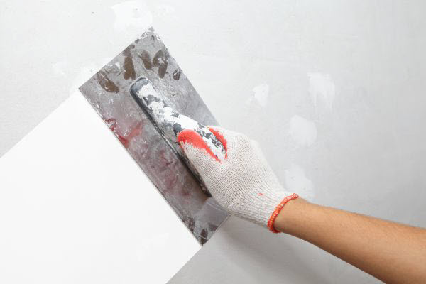 Plasterer Repairing And Levelling A Wall